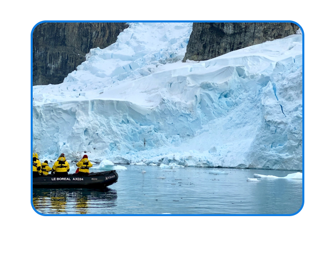 People on a raft in front of an iceberg.